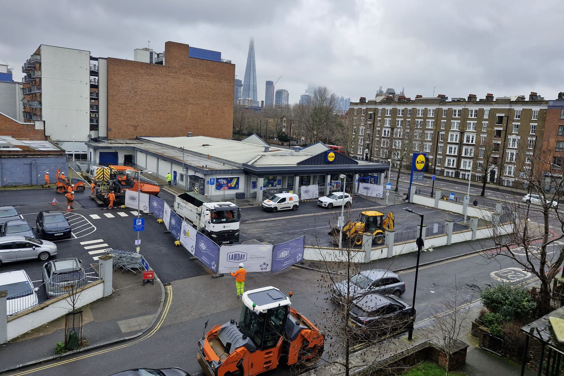 Aerial view of Lawday Civil Engineering resurfacing the customer car park at Lidl UK, Old Kent Road, London, with the Shard visible in the background
