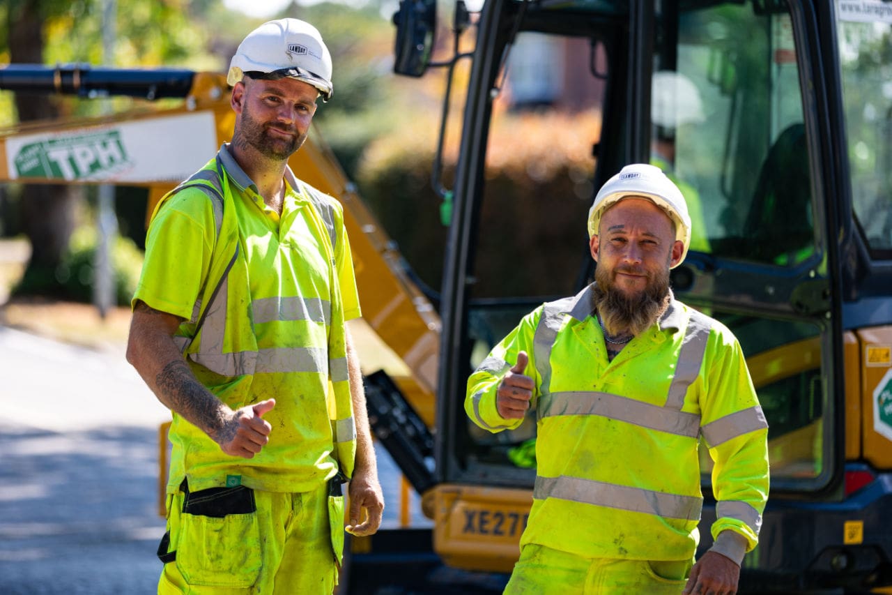 Two Lawday operatives giving a thumbs up beside an excavator on site